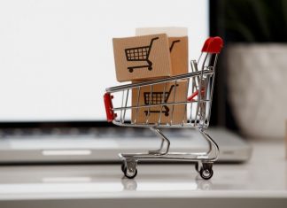 Many paper boxes in a small shopping cart on a laptop keyboard. Concepts about online shopping that consumers can buy things directly from their home or office just using a few clicks via web browser.